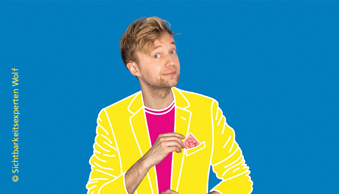 Marc Weide guckt verschmitzt in die Kamera und zieht eine Spielkarte aus der Einstecktasche seines Jackets