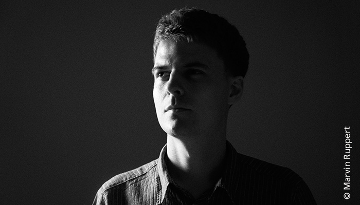 Stark weichgezeichnetes chwarz-weiß Bild eines Kopfes. Man erkennt das Gesicht nicht, aber es ist ein Portrait des Künstlers Alex Stoldt.