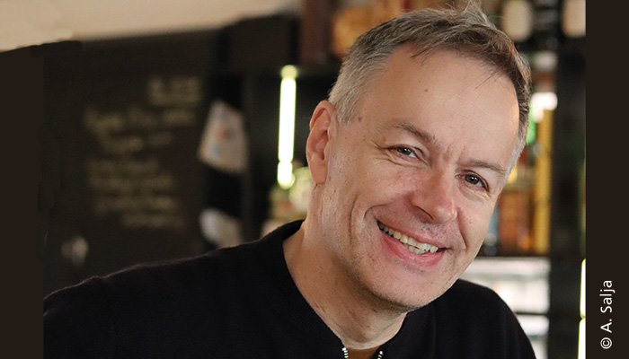 Kabarettist Steffen Möller lächelt in die Kamera. Der Hintergrund ist verschwommen, das Bild könnte in einem Restaurant aufgenommen worden sein.