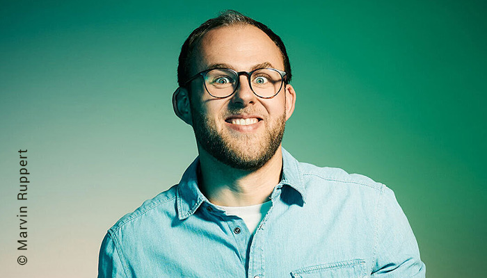 Portrait des Comedian Sven Bensmann grinsend und mit weit aufgerissenen Augen